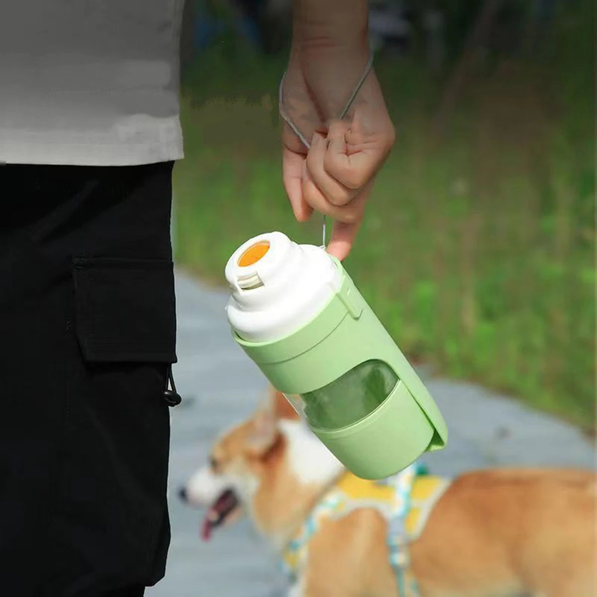 Green pet travel bottle carried by its wrist strap outdoors